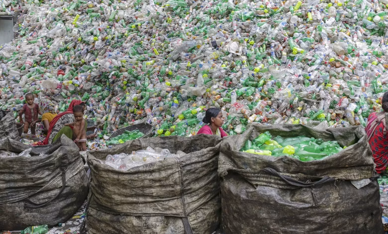 عاملات يفرزن الزجاجات البلاستيكية لإعادة تدويرها في مصنع في دكا، بنجلاديش