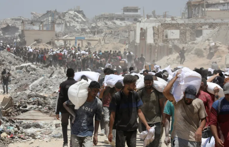 فلسطينيون يحملون إمدادات مساعدات دخلت غزة عبر إسرائيل