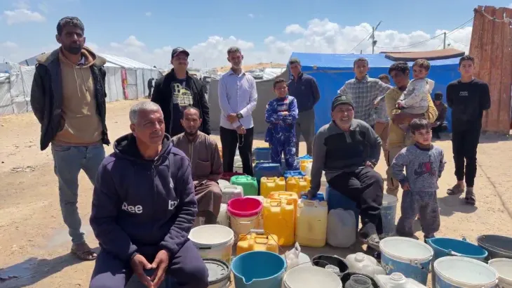 خيام نازحين في غزة تحيط بها النفايات وصهاريج مياه، وسط أطفال ينتظرون دورهم للحصول على مياه الشرب